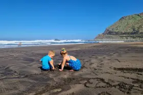 Dzieci budują zamki z piasku na czarnej plaży. Teneryfa atrakcje dla dzieci to raj dla małych odkrywców.